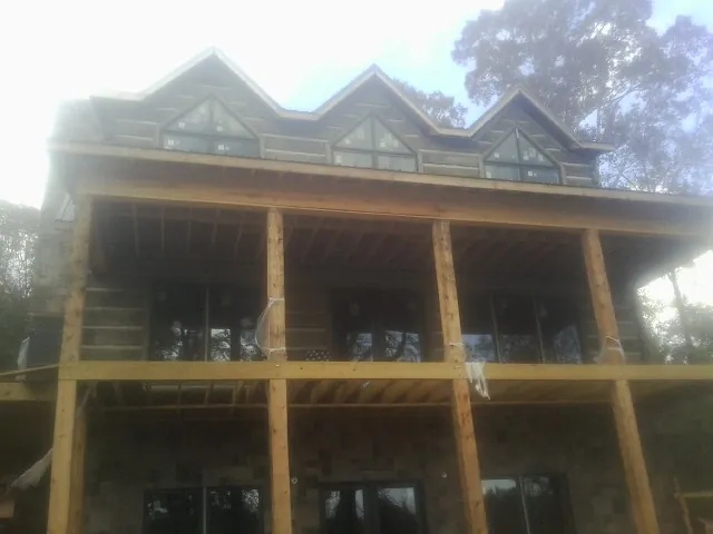 Dormers and porch framing on a large log home under construction — Roof Coating work by our crew in Gainesville