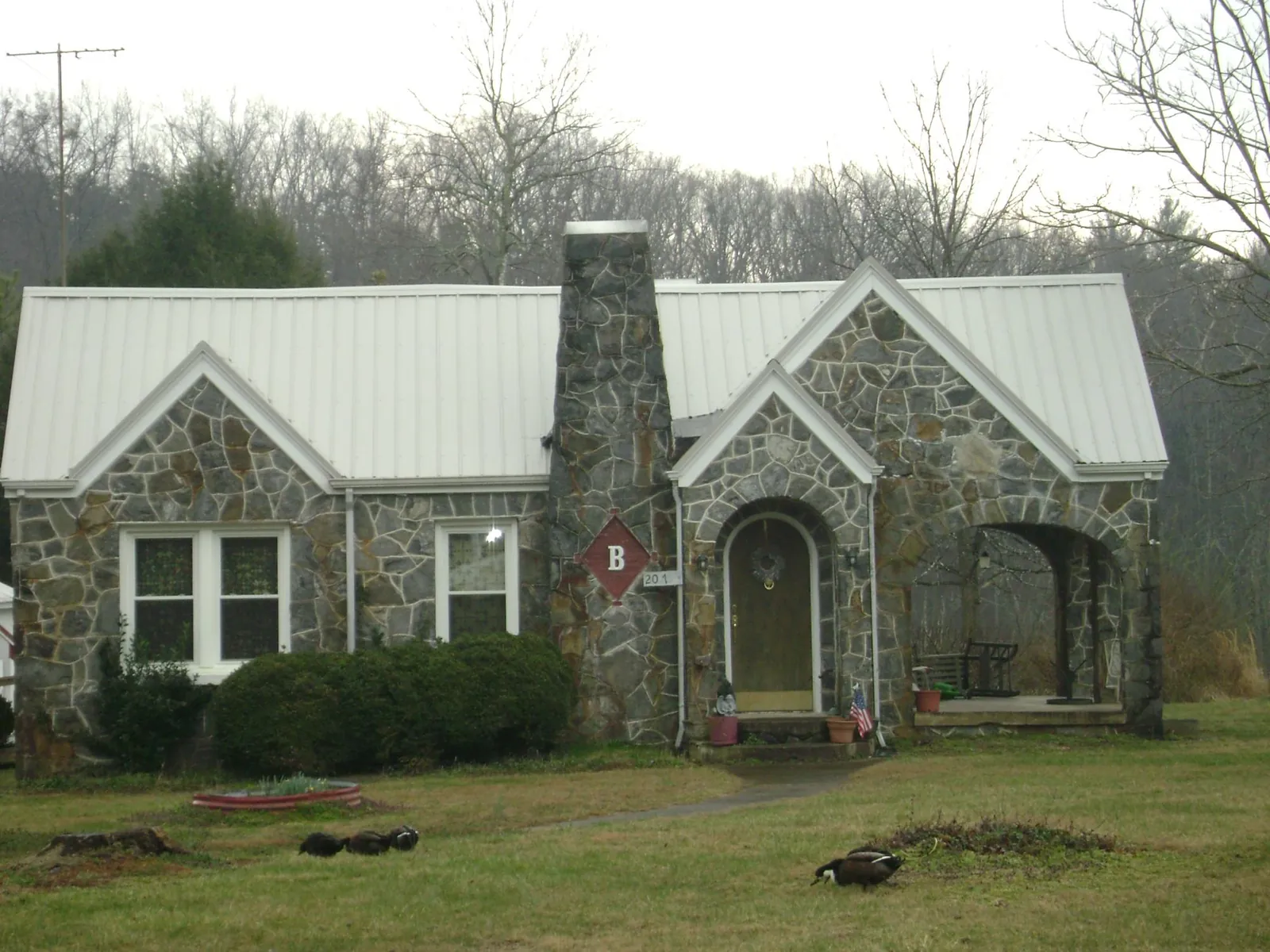 White metal roof on a stone cottage with steep gables in Gainesville