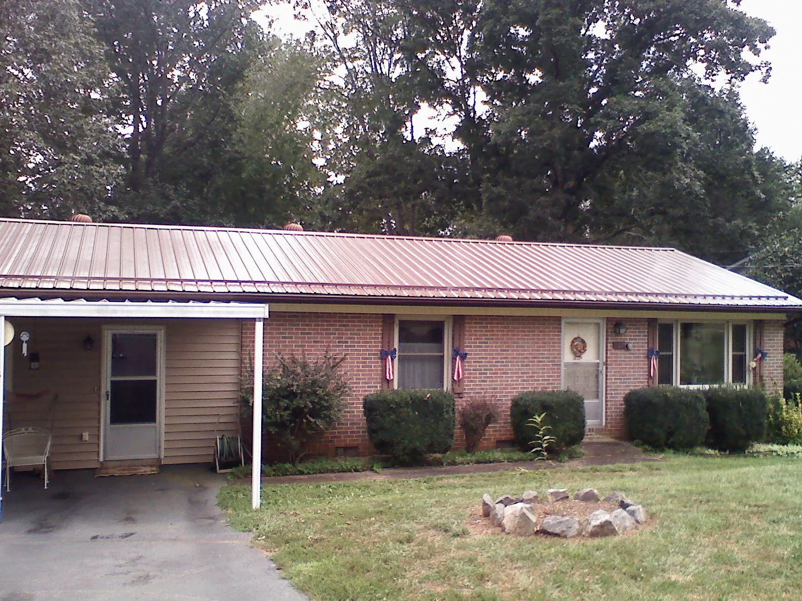 Bronze metal roof and carport on a brick ranch home — Roof Repair work by our crew in Gainesville