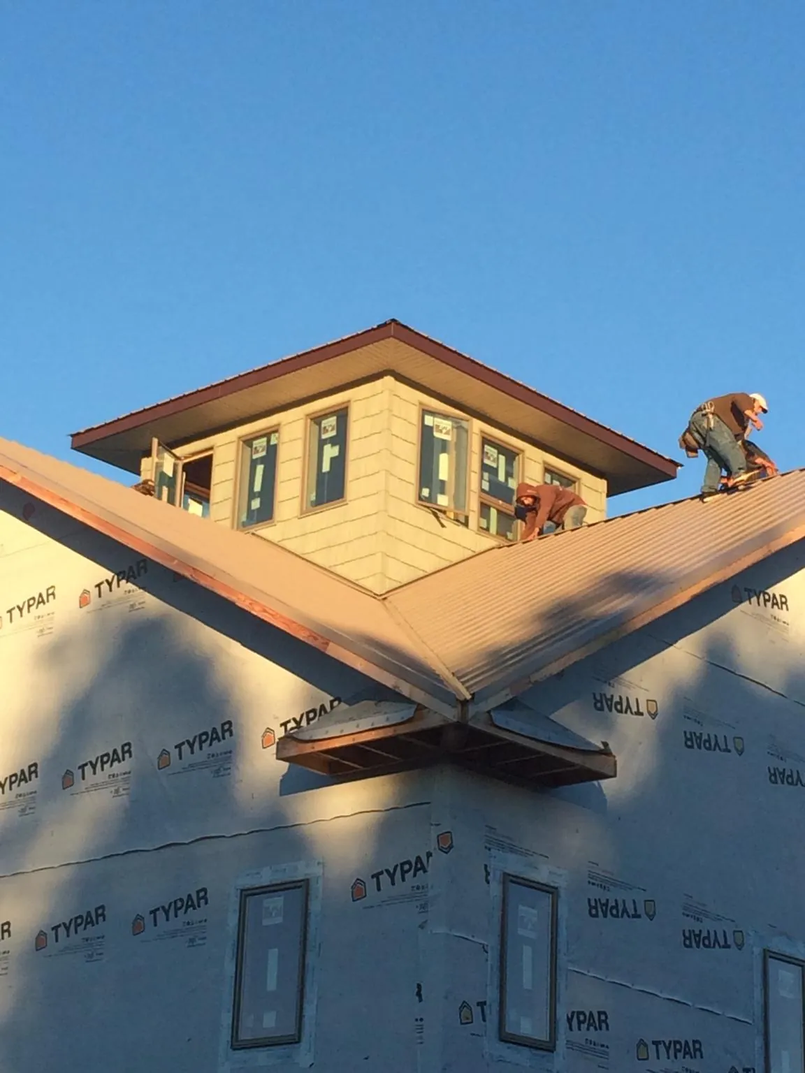 Roofers working around a rooftop cupola on a new metal roof at sunset — Roof Waterproofing in Gainesville by Roofing Brothers